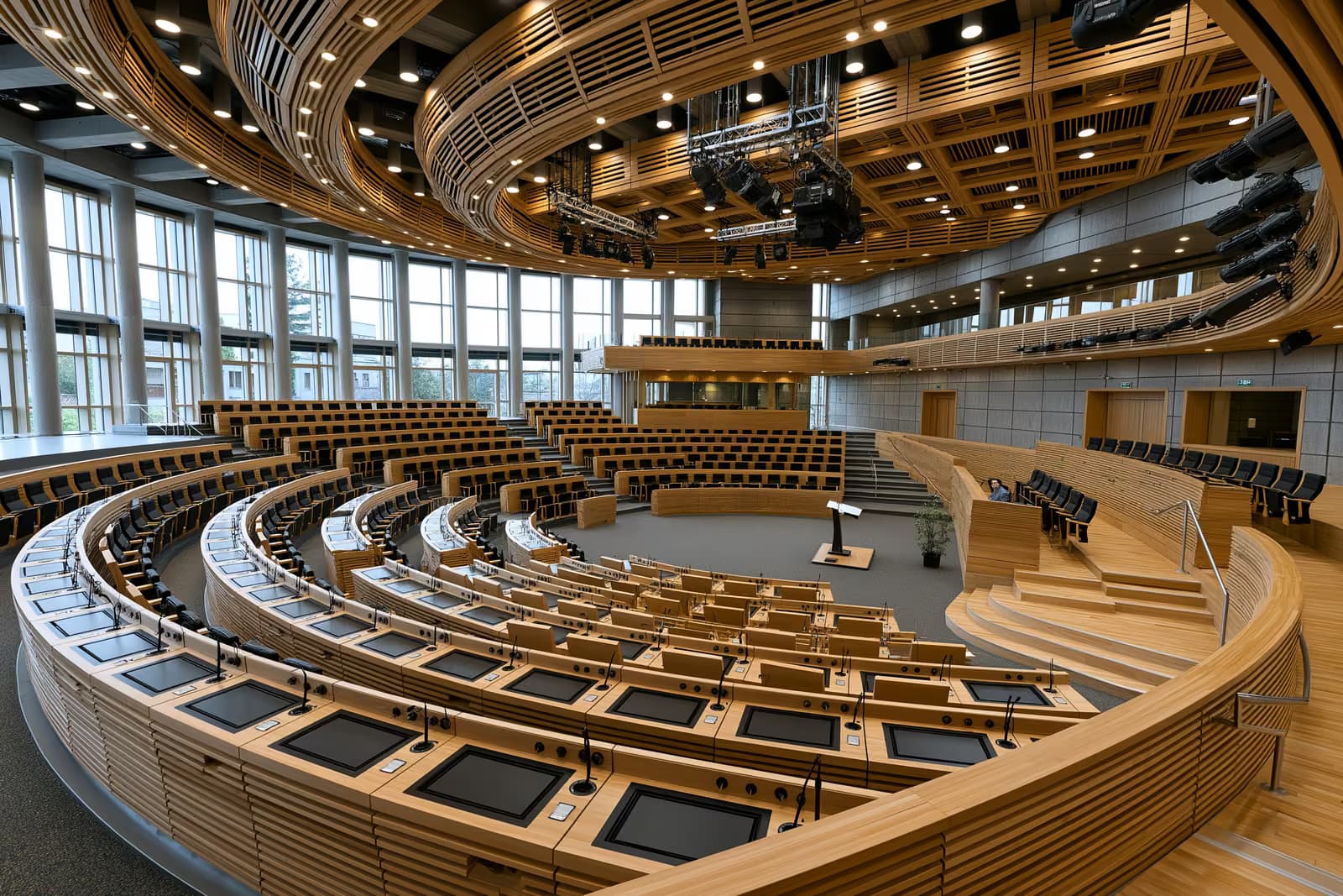Amplo interior de uma câmara plenária vazia do parlamento nacional antes de um debate.
