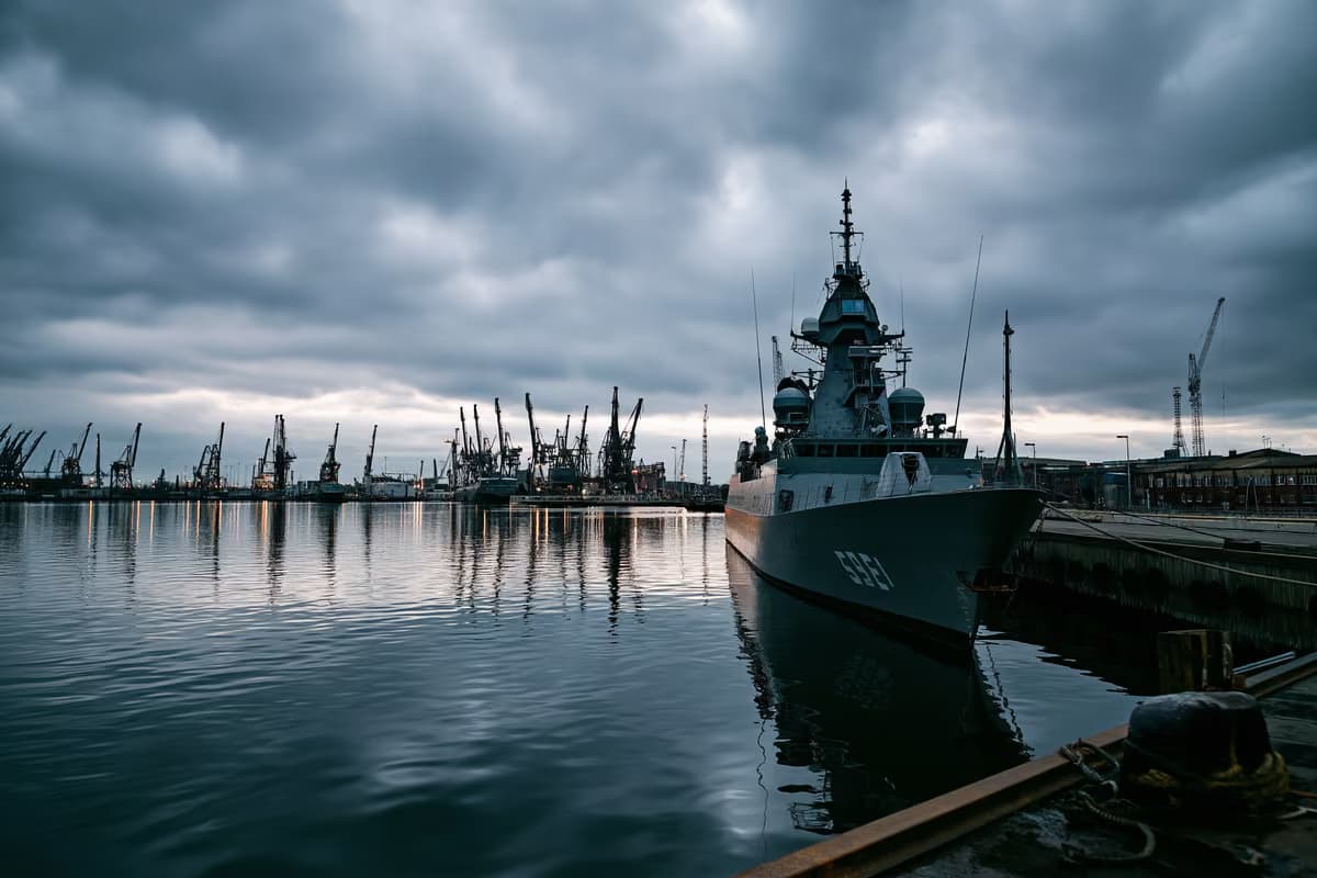 Um estaleiro naval cinzento sob um céu nublado, sugerindo investimento em defesa.