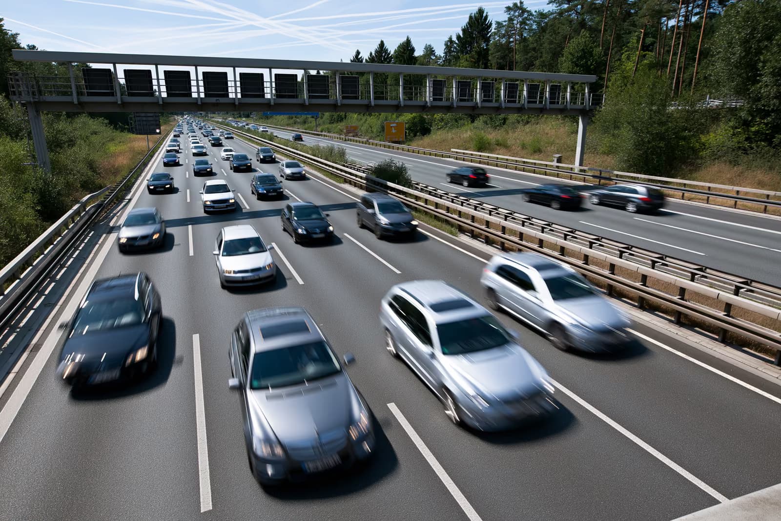 Carros trafegando em um trajeto fluido em uma rodovia alemã em um dia ensolarado de verão.