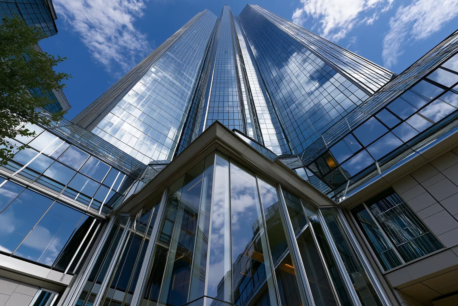 Uma moderna torre bancária de vidro em um distrito financeiro alemão sob um céu claro.